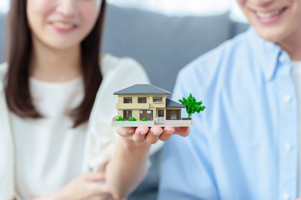 マイホーム購入を検討する夫婦と住宅の模型