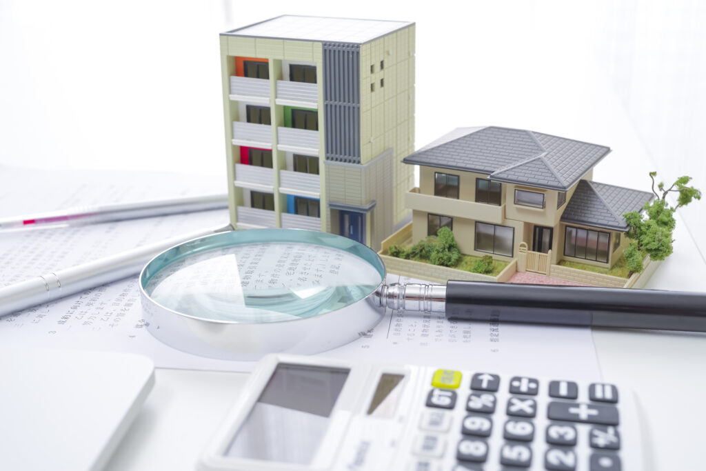 住宅ローンを比較検討するための資料と住宅模型、電卓のイメージ